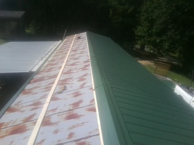 Old rusted panels beside newly installed green metal roofing — Wind Damage Roof Repair by Roofing Brothers in Liberty Hill