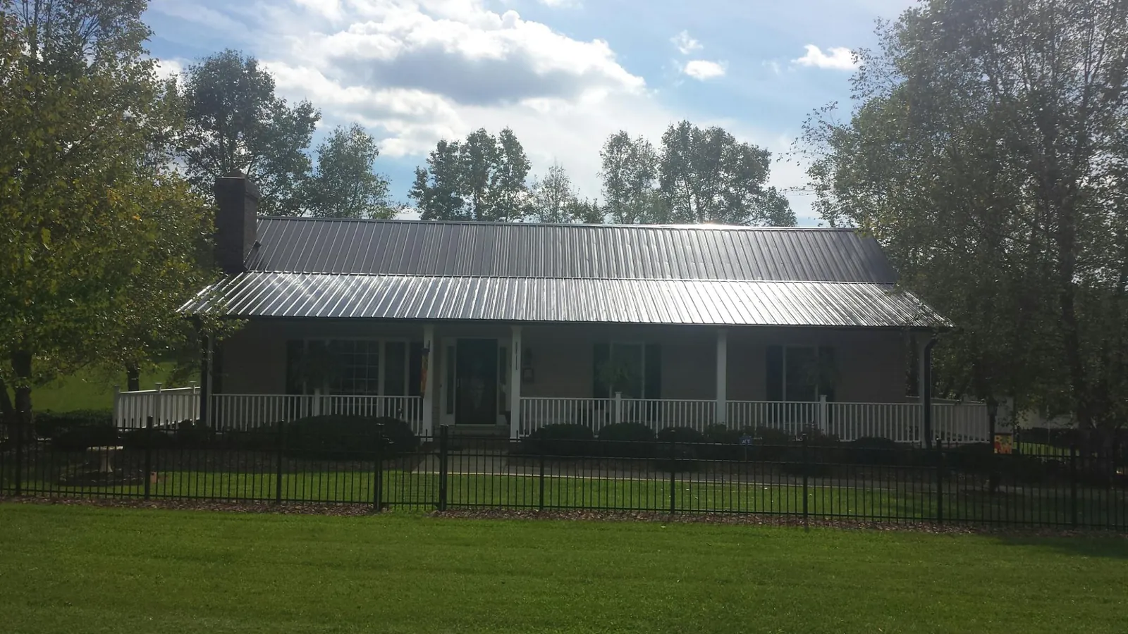 Gray metal roof on a brick ranch with a full width front porch — Gutter Guard Installation work by our crew in Liberty Hill